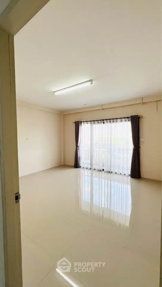 Spacious empty room with large window and curtains, perfect for customization.