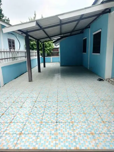 Spacious covered outdoor area with tiled flooring and blue walls, perfect for gatherings.