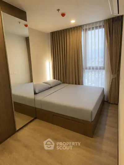 Modern bedroom with large mirror and floor-to-ceiling window in a stylish apartment.