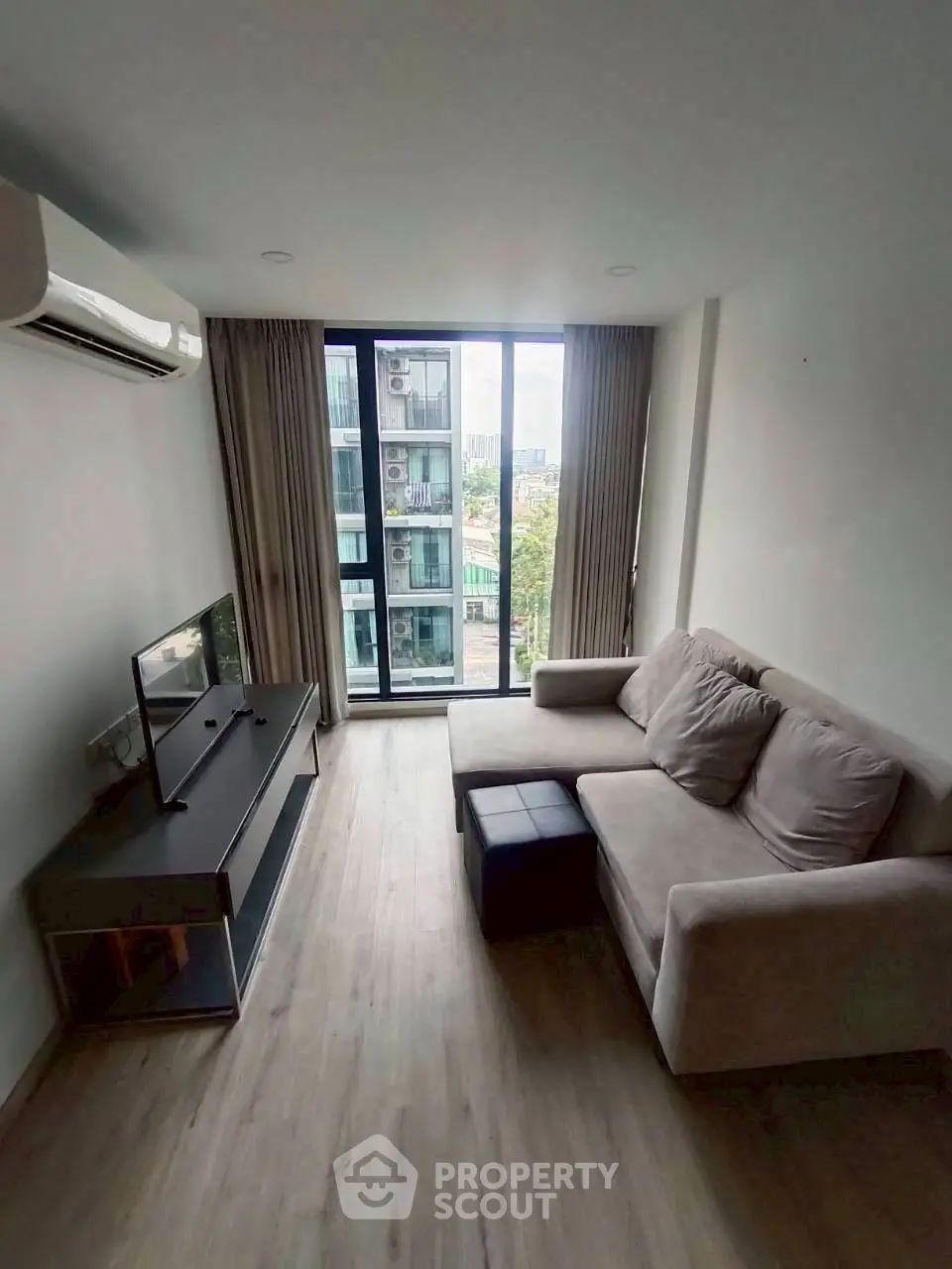 Modern living room with large window and cozy sofa in a high-rise apartment.
