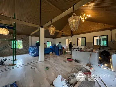 Spacious under-construction living room with high ceilings and modern lighting fixtures