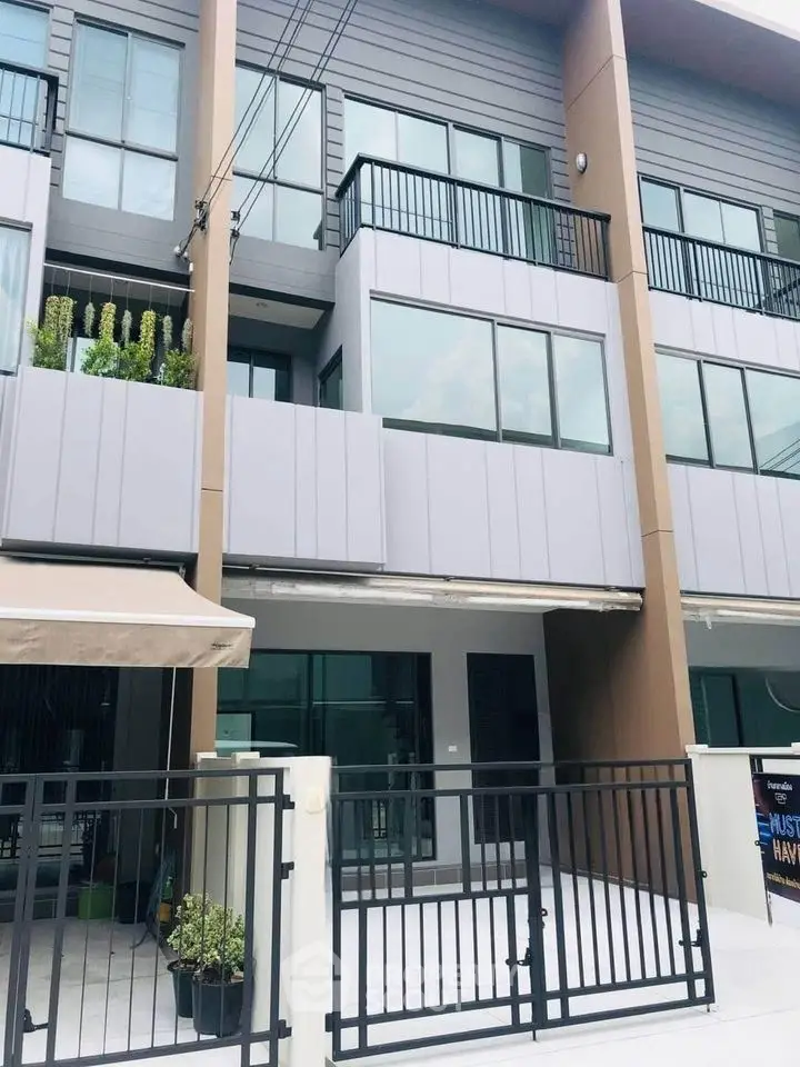 Modern townhouse exterior with sleek design and spacious balcony in urban setting.