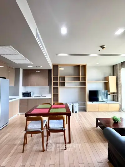 Modern open-layout living room with sleek kitchen and dining area, featuring stylish furniture and ample natural light.