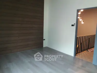 Spacious empty room with modern wooden accent wall and stylish lighting.