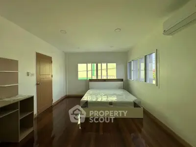 Spacious bedroom with wooden flooring and natural light in modern apartment