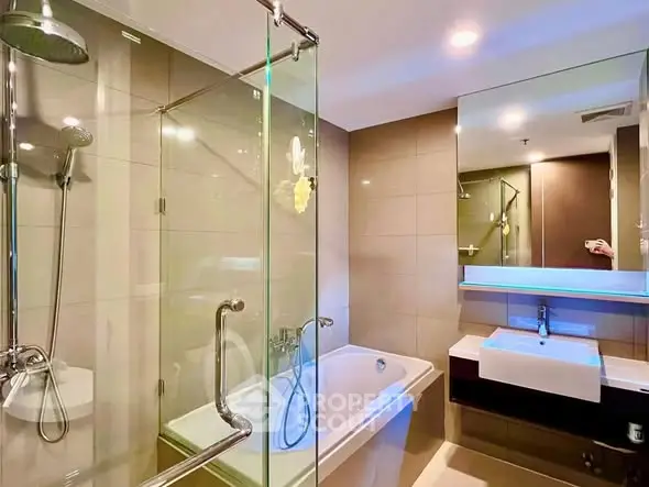 Modern bathroom with glass shower and bathtub in luxury apartment.