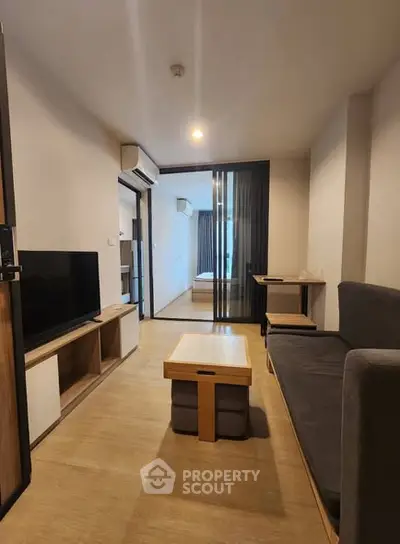 Modern living room with sleek furniture and open view to bedroom