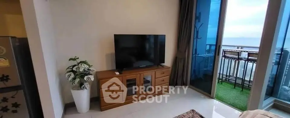 Modern living room with TV and balcony offering stunning ocean view