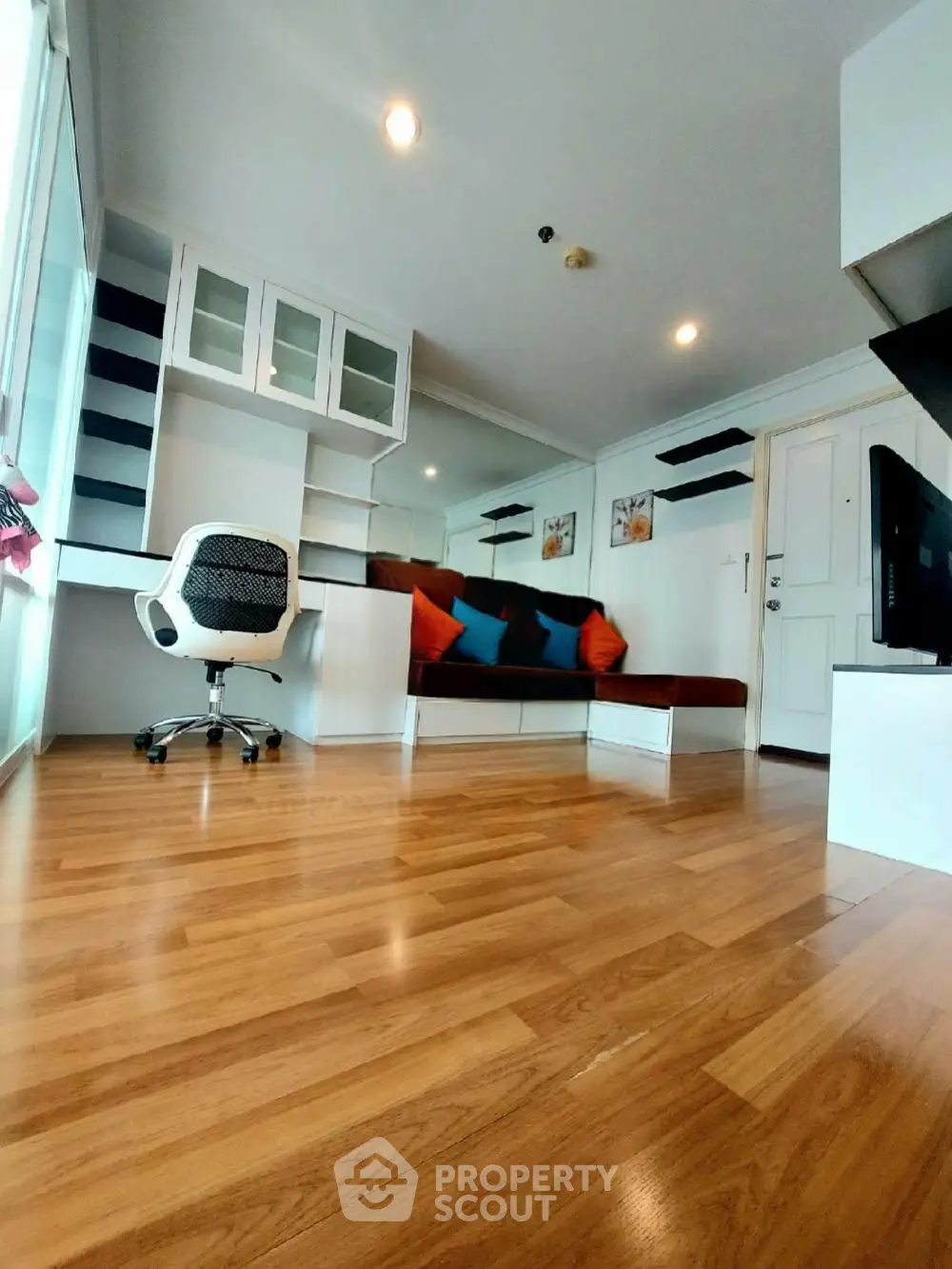 Modern living room with wooden flooring, built-in shelves, and cozy seating area.
