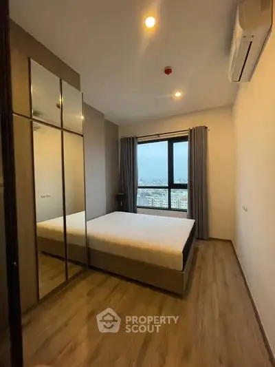Modern bedroom with mirrored wardrobe and city view window
