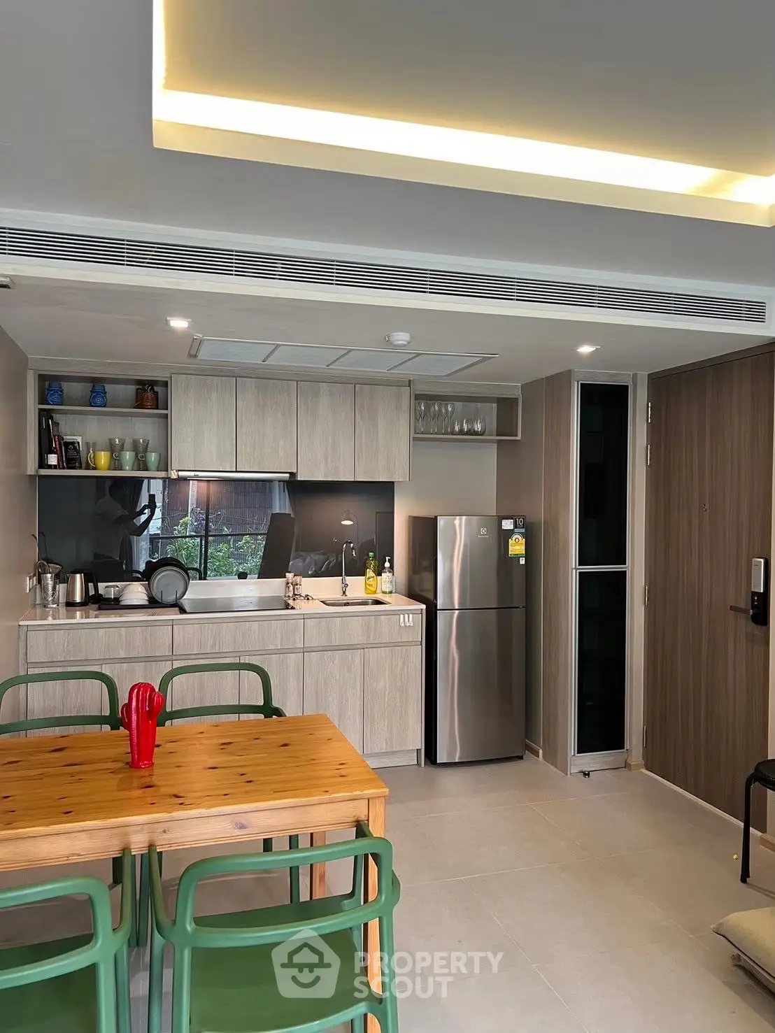Modern kitchen with open layout and dining area, featuring stainless steel appliances and wooden cabinetry.