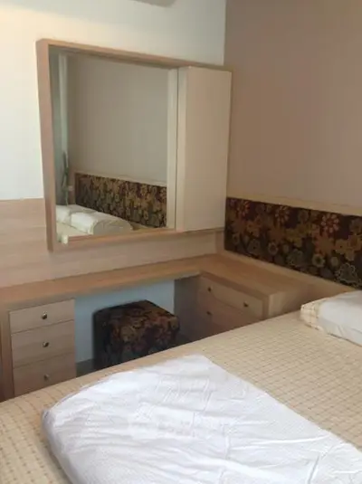 Cozy bedroom with stylish wooden furniture and floral accents, perfect for a comfortable living space.