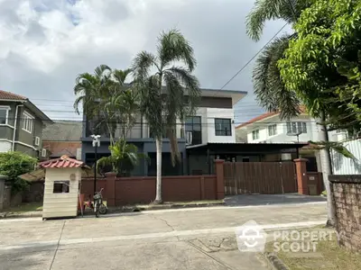 Modern two-story house with palm trees and gated entrance in suburban neighborhood