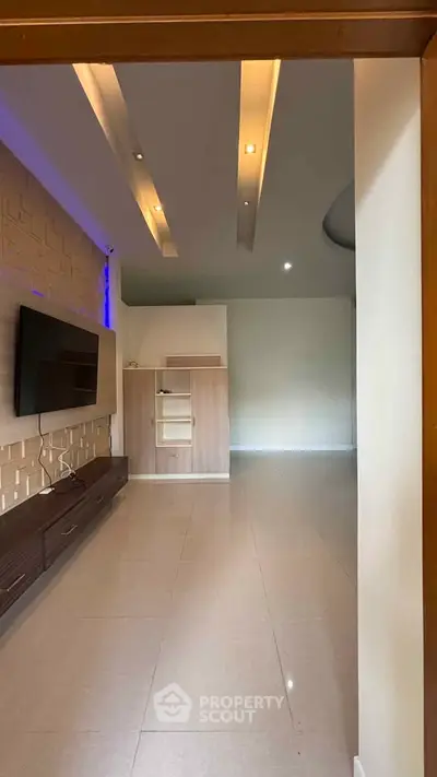Modern living room with sleek design and built-in TV unit, featuring recessed lighting and neutral tones.