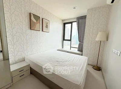 Modern bedroom with city view, stylish decor, and ample natural light.