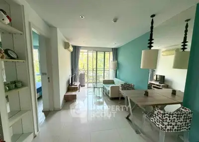 Modern living room with teal accent wall and large windows opening to a balcony.