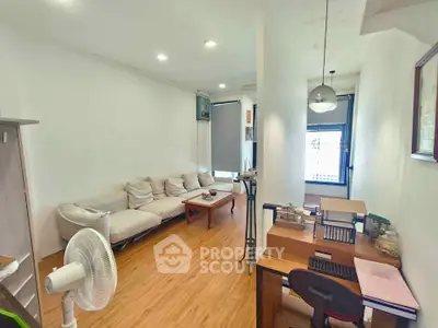 Spacious living room with modern decor and natural light, featuring a cozy sofa and a functional workspace.