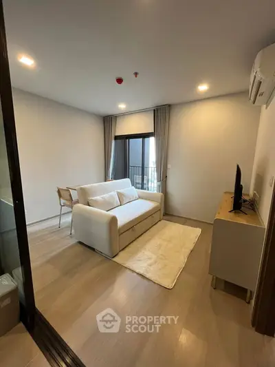 Modern living room with cozy sofa and TV, featuring elegant wooden flooring and natural light.