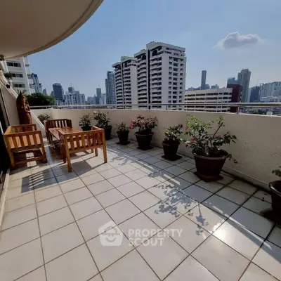 Spacious balcony with city skyline view and elegant outdoor seating, perfect for relaxation.