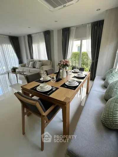 Elegant living room with dining area, featuring modern furniture and large windows for natural light.