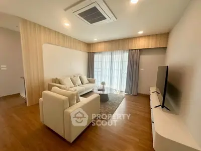Modern living room with cozy seating and large TV, featuring elegant wooden flooring and soft lighting.