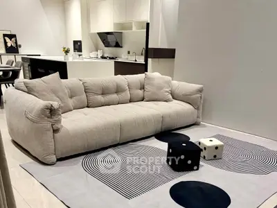 Modern living room with plush sofa and stylish kitchen in open layout apartment.
