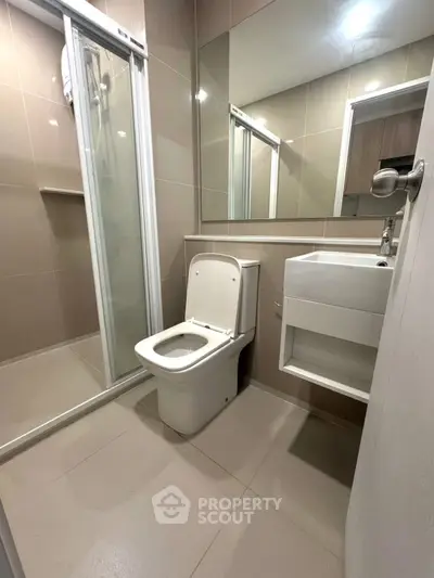 Modern bathroom with sleek shower and compact vanity in a contemporary apartment.