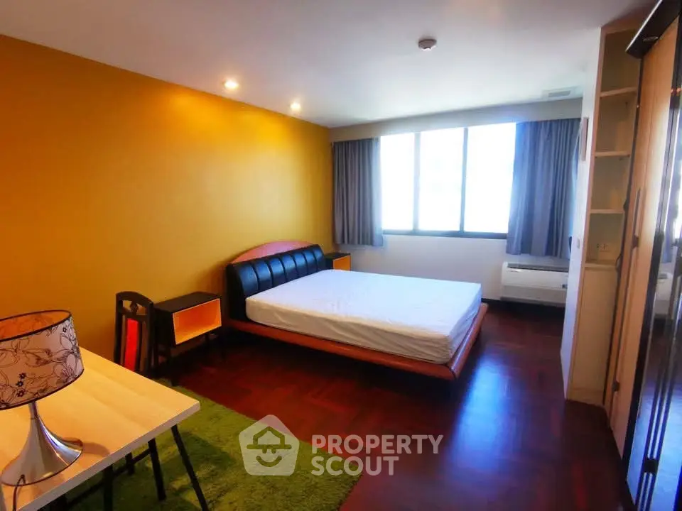 Spacious bedroom with modern furnishings and large window for natural light.