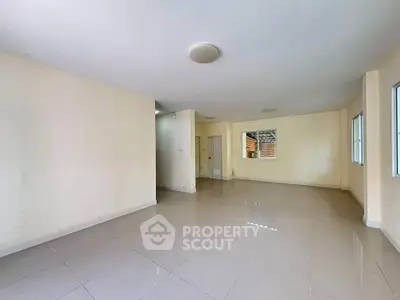 Spacious empty living room with tiled flooring and large windows for natural light.