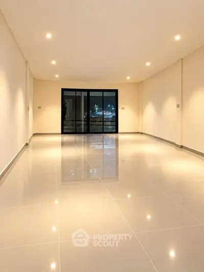Spacious empty living room with glossy tiled floors and large windows for natural light.