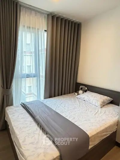 Cozy bedroom with large window and elegant curtains in modern apartment