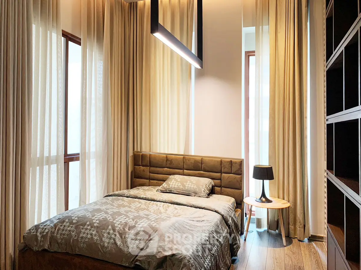 Luxurious bedroom with elegant lighting and floor-to-ceiling curtains in modern apartment.