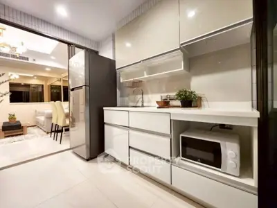 Modern kitchen with sleek cabinetry and open layout leading to elegant dining area.