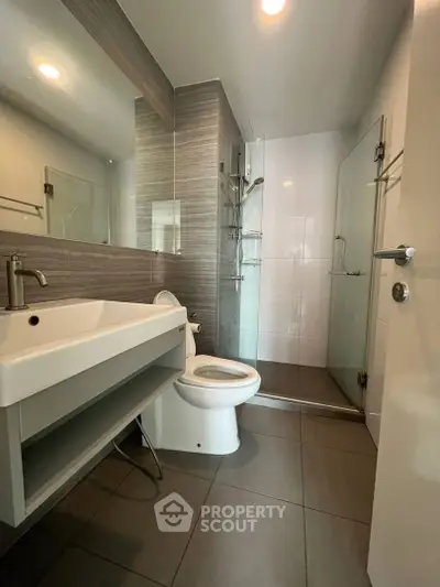 Modern bathroom with sleek fixtures and glass shower enclosure in a contemporary apartment.