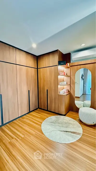 Modern bedroom with wooden flooring and built-in wardrobe, featuring a stylish mirror and cozy seating area.