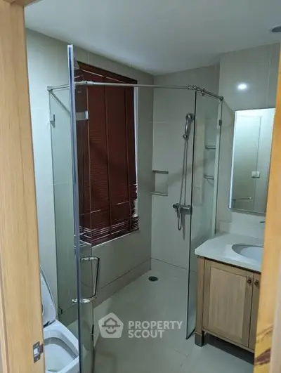 Modern bathroom with glass shower enclosure and wooden vanity