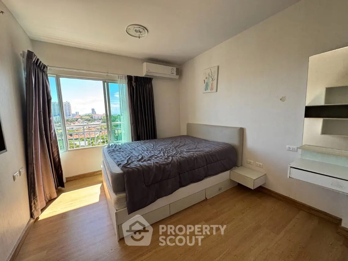 Spacious bedroom with city view and modern furnishings in a high-rise apartment.