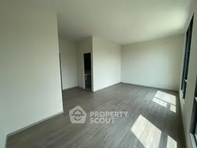 Spacious empty room with large windows and wooden flooring, perfect for customization.