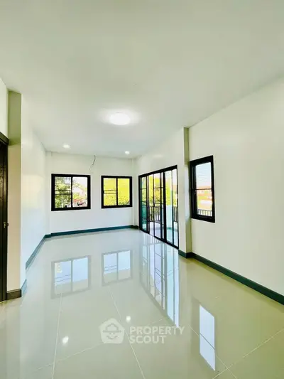 Spacious empty living room with large windows and glossy tiled floor