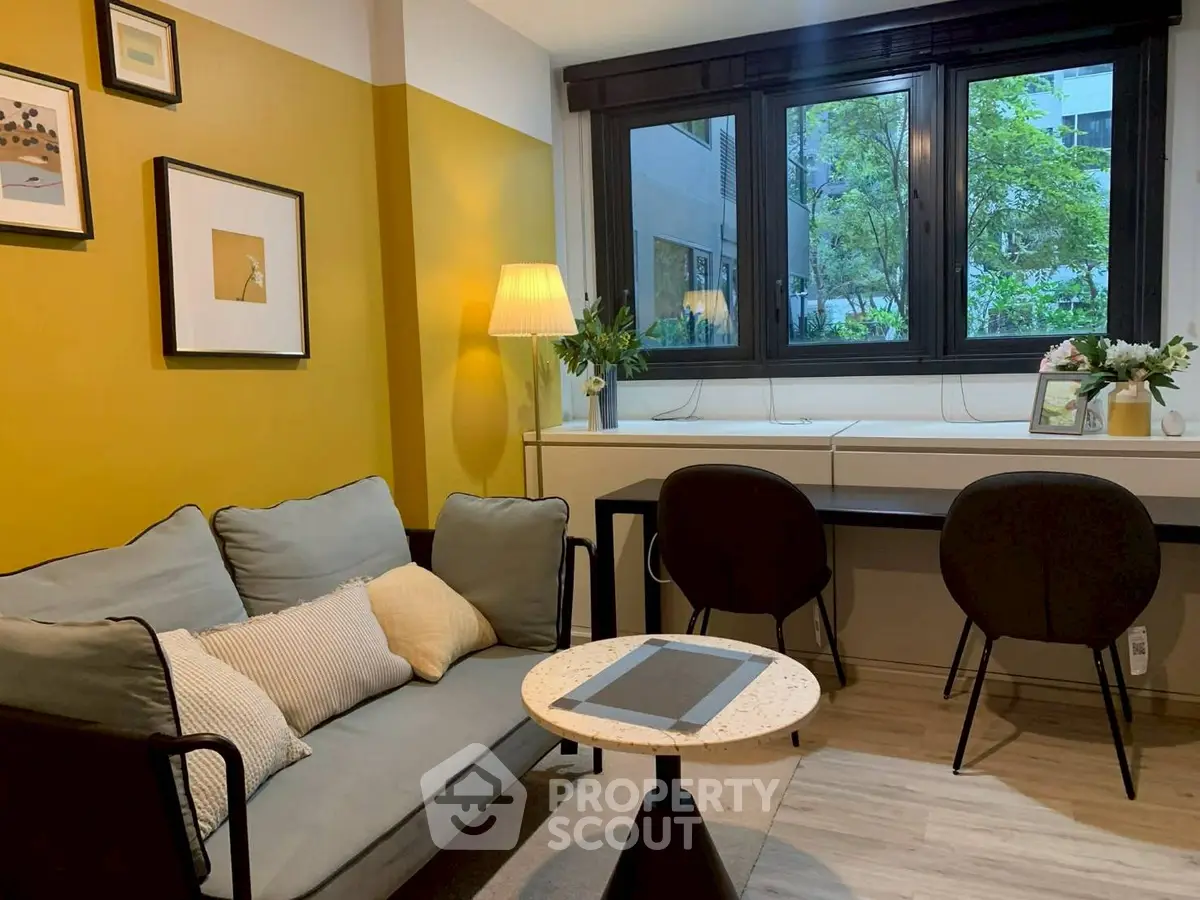 Chic living room with modern decor, large window, and cozy seating area in urban apartment.
