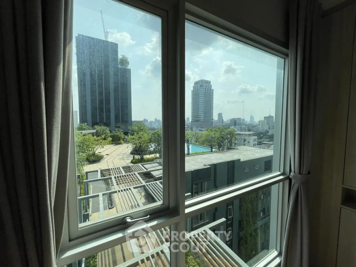 Stunning cityscape view from modern apartment window with lush greenery and skyline.