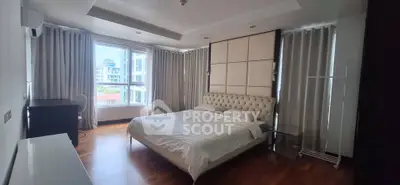 Spacious bedroom with elegant decor and large windows offering natural light and city views.