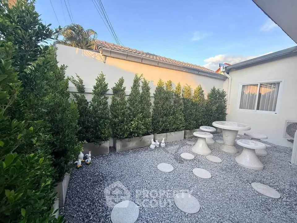 Charming outdoor garden area with stone seating and lush greenery, perfect for relaxation and entertainment.