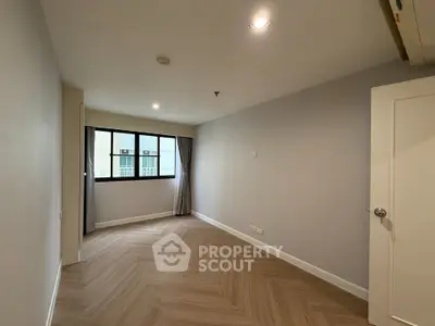Spacious empty room with large window and elegant flooring in modern apartment.