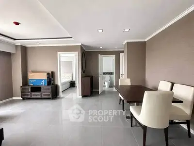 Spacious modern living room with dining area and view into bedroom, featuring sleek furniture and neutral tones.