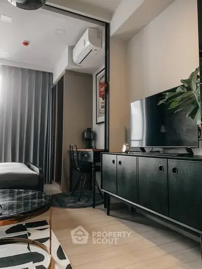 Modern living room with sleek furniture and stylish decor, featuring a TV and air conditioning unit.