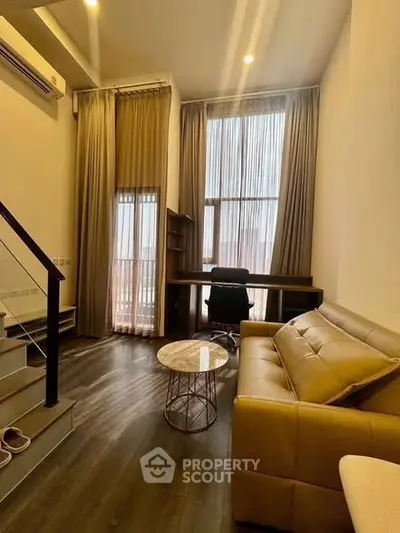 Modern living room with high ceilings, stylish sofa, and workspace area, perfect for urban living.
