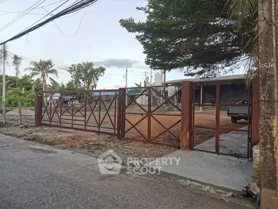 Spacious property with secure metal gate and lush greenery, ideal for development.