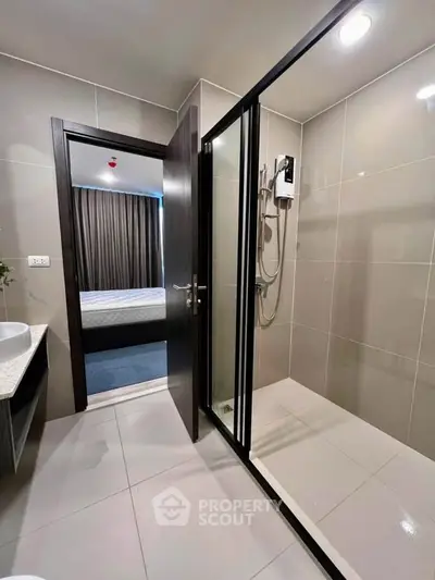 Modern bathroom with glass shower and view into a stylish bedroom