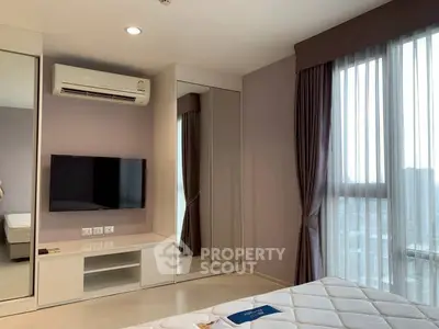Modern bedroom with large windows, mirrored closet, and wall-mounted TV in a stylish apartment.